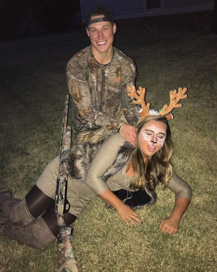 a man and woman with deer antlers on their heads are sitting in the grass