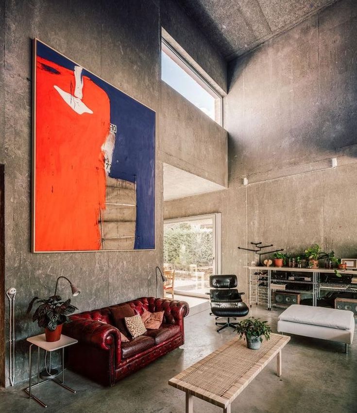 a living room filled with furniture and a large painting on the wall above it's windows