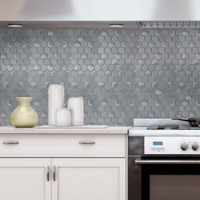 a stove top oven sitting inside of a kitchen next to a wall covered in hexagonal tiles