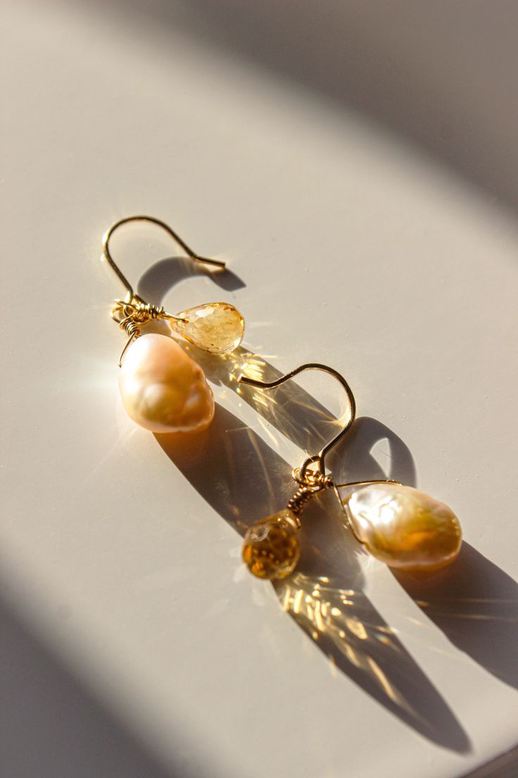 PRODUCT DESCRIPTION Inspired by the seas' motion and the rise and fall of the tide, there's an element of nature in this piece. Complete with a golden natural citrine and a unique pair of baroque pearl droplets, this set of earrings are full of luxurious. You are fine to shower in our gold-filled jewelry. Get it wet, wear it for life! Freshwater Pearl and Natural citrine Earrings Designed in New Zealand 14k Gold-filled with jeweler's brass (at least 5% real gold): A 14K Gold-filled piece is a st Yellow Gold Teardrop Pearl Earrings With Gemstone, Gold Briolette Pearl Earrings, Gold Pearl Earrings With Natural Stones, Gold Drop Pearl Earrings With Gemstones, Gold Briolette Pearl Gemstone Earrings, Pear-shaped Gold Pearl Earrings With Gemstones, Gold Briolette Pearl Earrings With High Luster, Gold Pear-shaped Citrine Jewelry, Pear-shaped Citrine Gold Jewelry