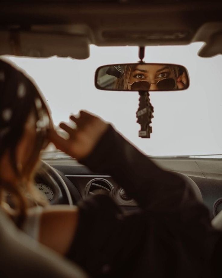 a woman is seen in the rear view mirror of a car