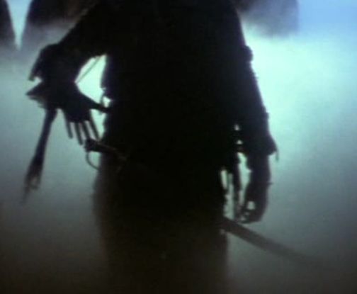 the silhouette of a person holding two swords in front of foggy skies and trees