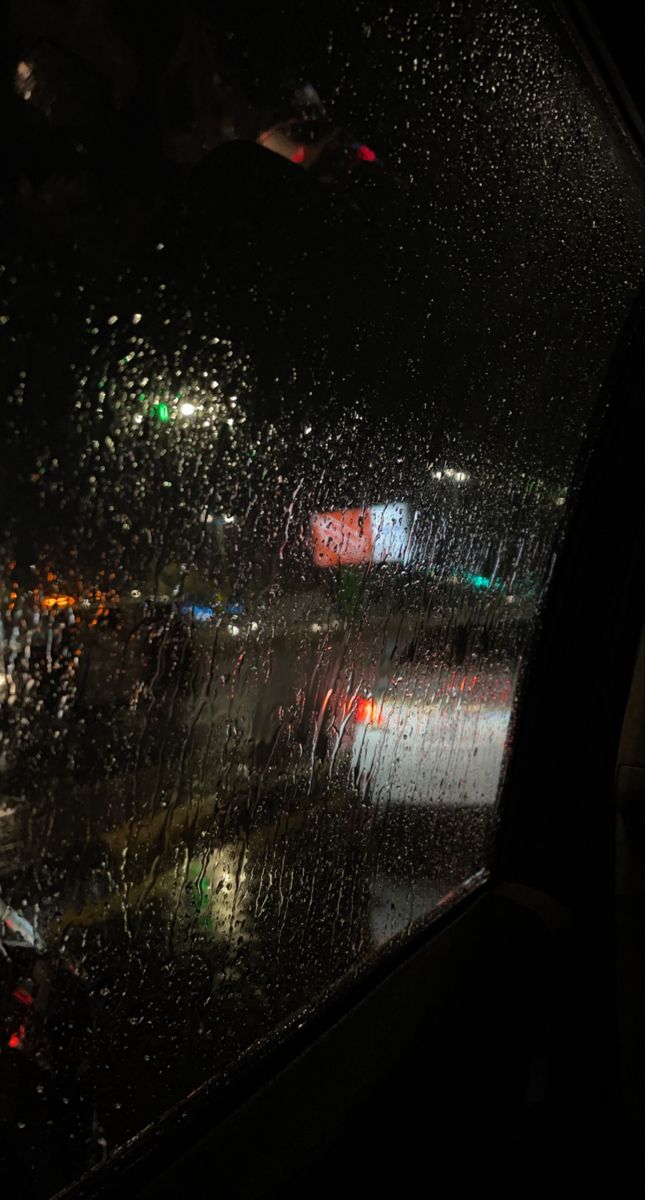 rain is falling on the windshield of a car at night