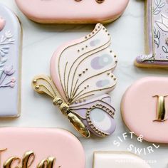 decorated cookies with the letter i and butterfly on them are arranged in pastel colors