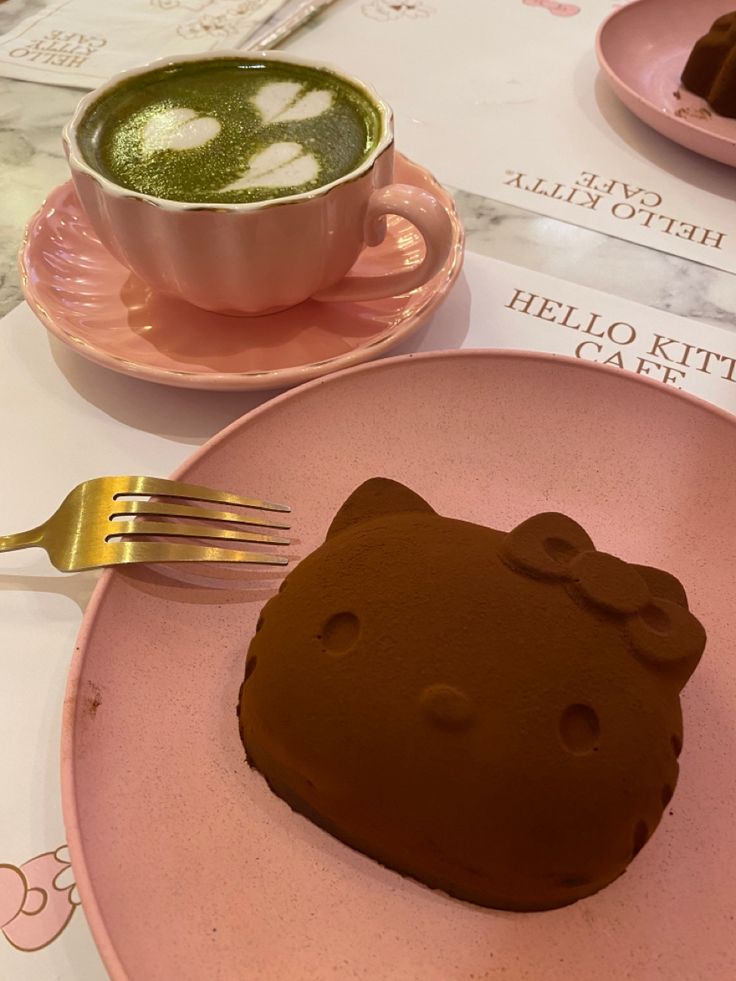 a pink plate topped with a piece of cake next to a cup of coffee