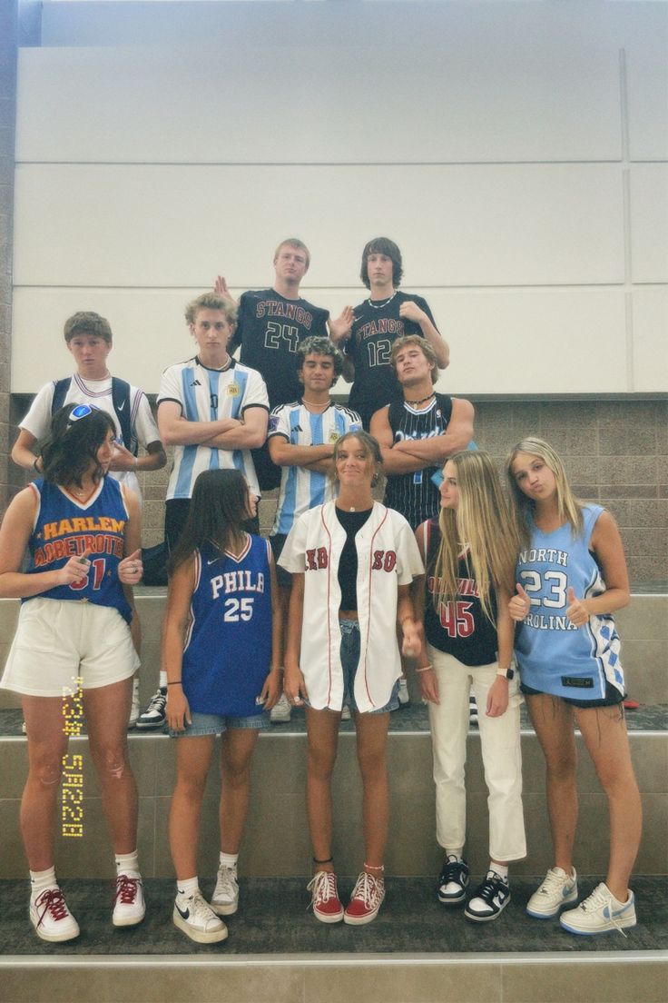 a group of young people standing next to each other in front of a wall and stairs