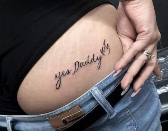 a woman's stomach with the words yes daddy tattooed on her lower side belly