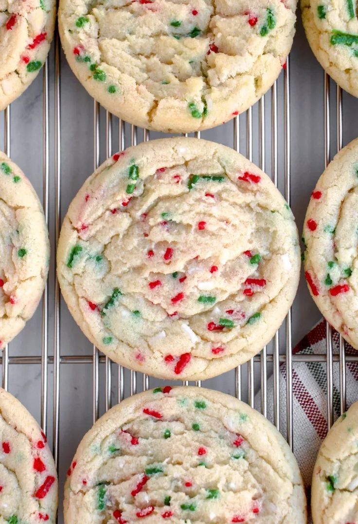 many cookies with sprinkles are cooling on a rack