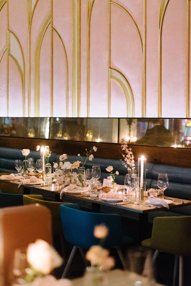 a long table is set up with candles and flowers in front of the wall behind it