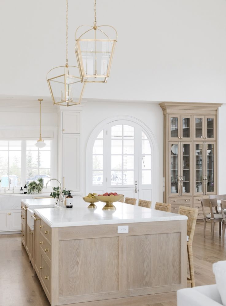 a large kitchen with an island in the middle and chairs around it, all white