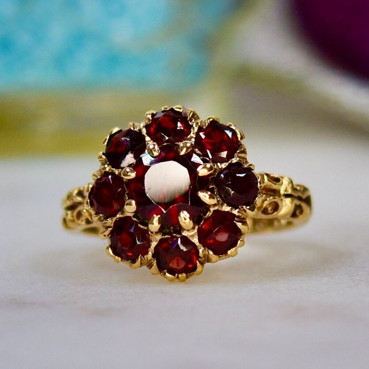 There is something very pleasing about the combination of juicy red garnets and warm yellow gold. This pretty example has a central 5mm stone with eight smaller stones forming a halo. The overall diameter is 13mm. There is a partial maker or sponsors mark, I believe of ATC, alongside a full hallmark for 9ct gold, having been assayed in London in 1973. UK Ring Size: I 1/2 US Ring Size: 4 ¾ The weight is 3.01g. Please note, this item is not new and is sold as shown and described. Vintage items wil Yellow Gold Garnet Cluster Ring As Gift, Garnet Birthstone Cluster Ring, Heirloom Style Red Garnet Cluster Ring, Heirloom Red Garnet Cluster Ring, Red Garnet Cluster Ring, Heirloom Style Round Garnet Cluster Ring, Heirloom Style Garnet Cluster Ring, Heirloom Garnet Cluster Ring, Antique Red Cluster Ring Gift