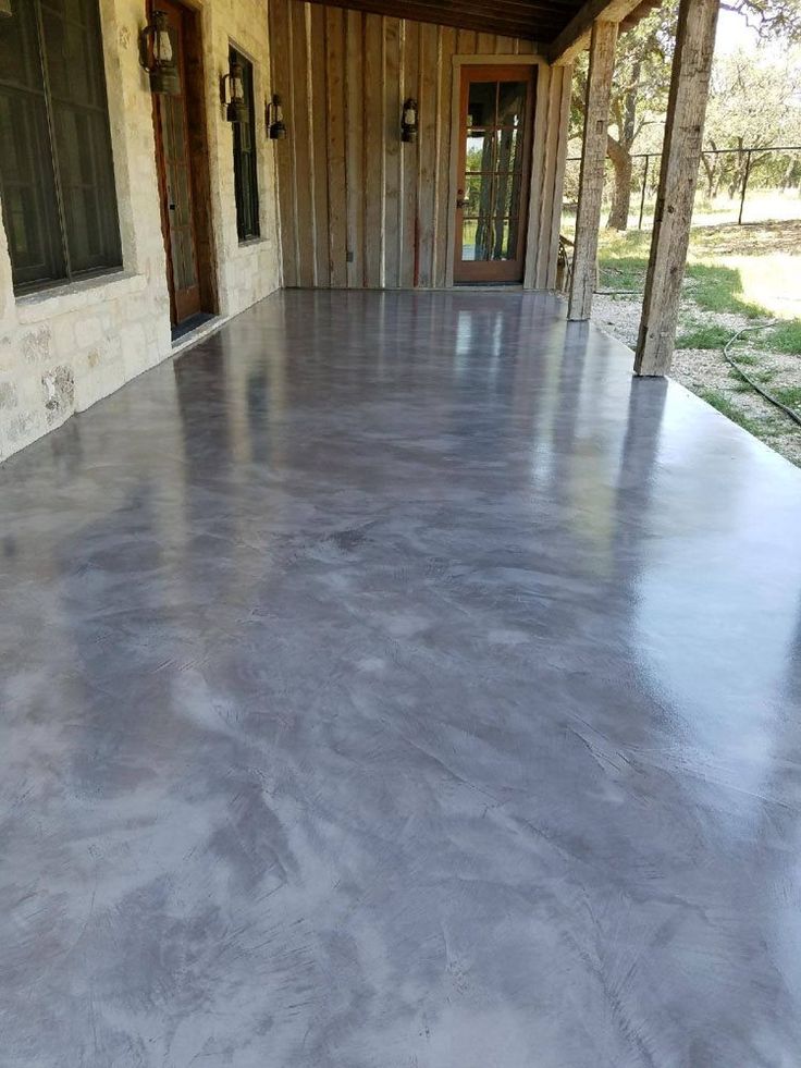 an empty porch with concrete flooring and wood paneling on the side of it