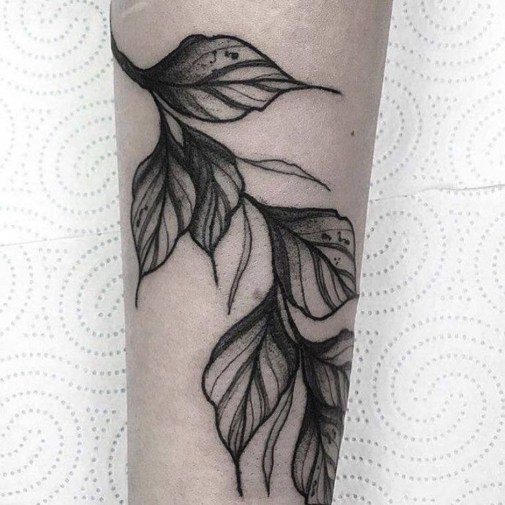 a black and white photo of a bird with leaves on it's leg tattoo