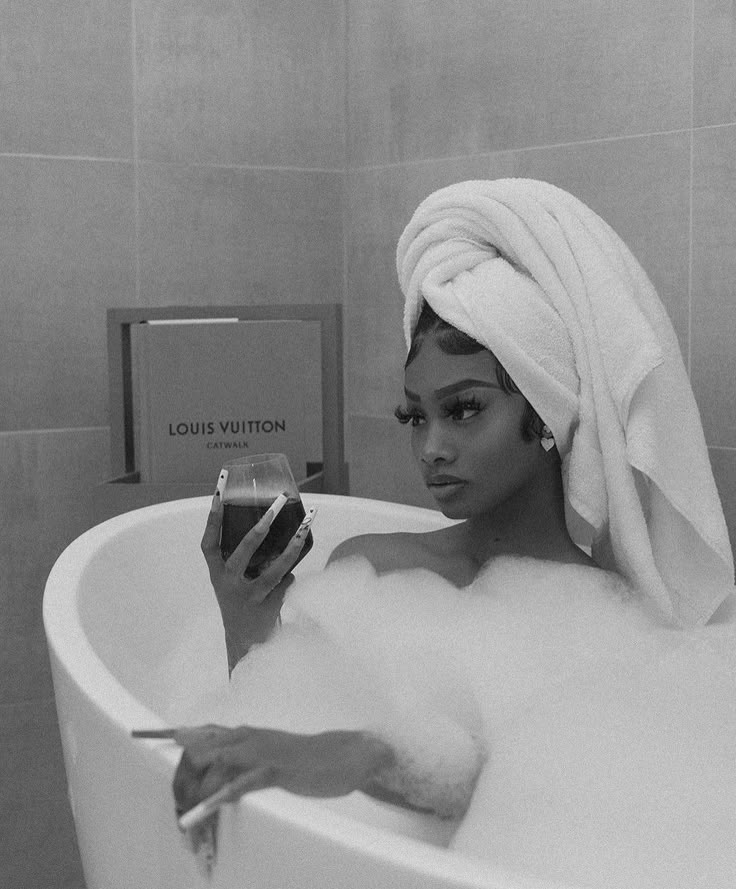 a woman in a bathtub with a towel on her head holding a cell phone