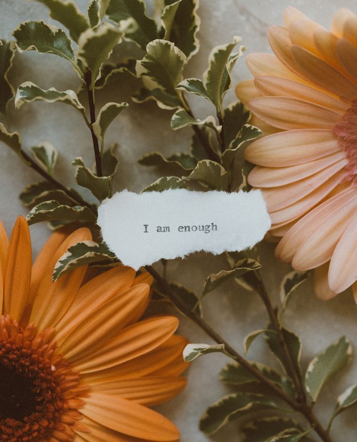 some flowers and a piece of paper with the words i am enough written on it