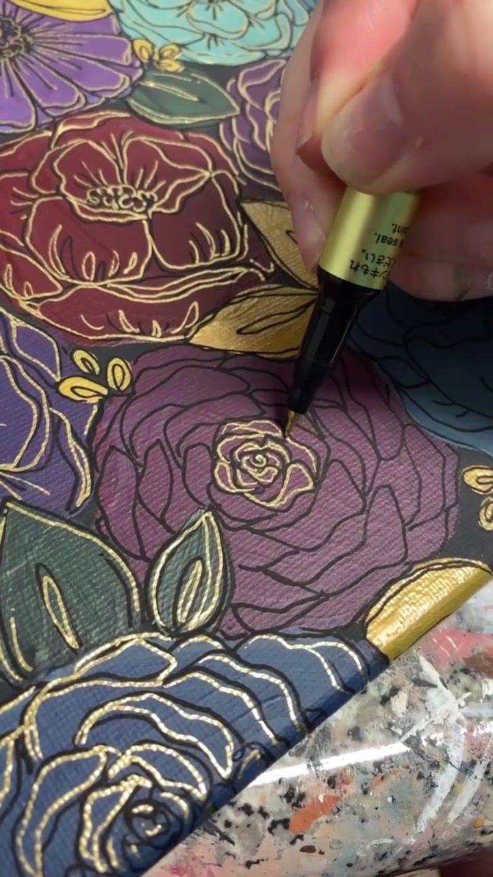 a person is using a marker to draw flowers on a piece of fabric with gold foil