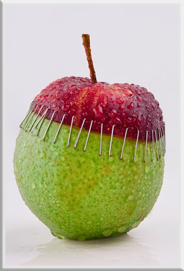 an apple with pins sticking out of it's side and the top half covered in fruit coloring