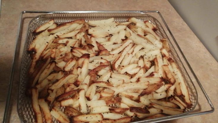 french fries in a glass dish on a counter top, ready to be cooked and put into the oven