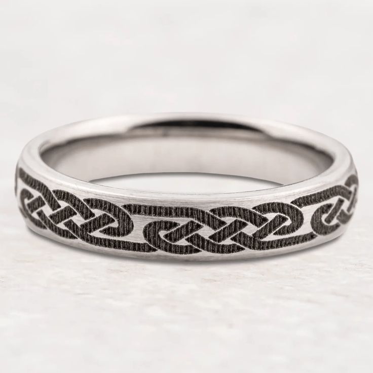 a wedding ring with an intricate design on it's side, sitting on a white surface