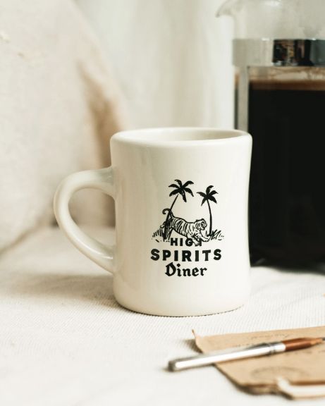 a coffee mug sitting on top of a table next to a cup and spoons