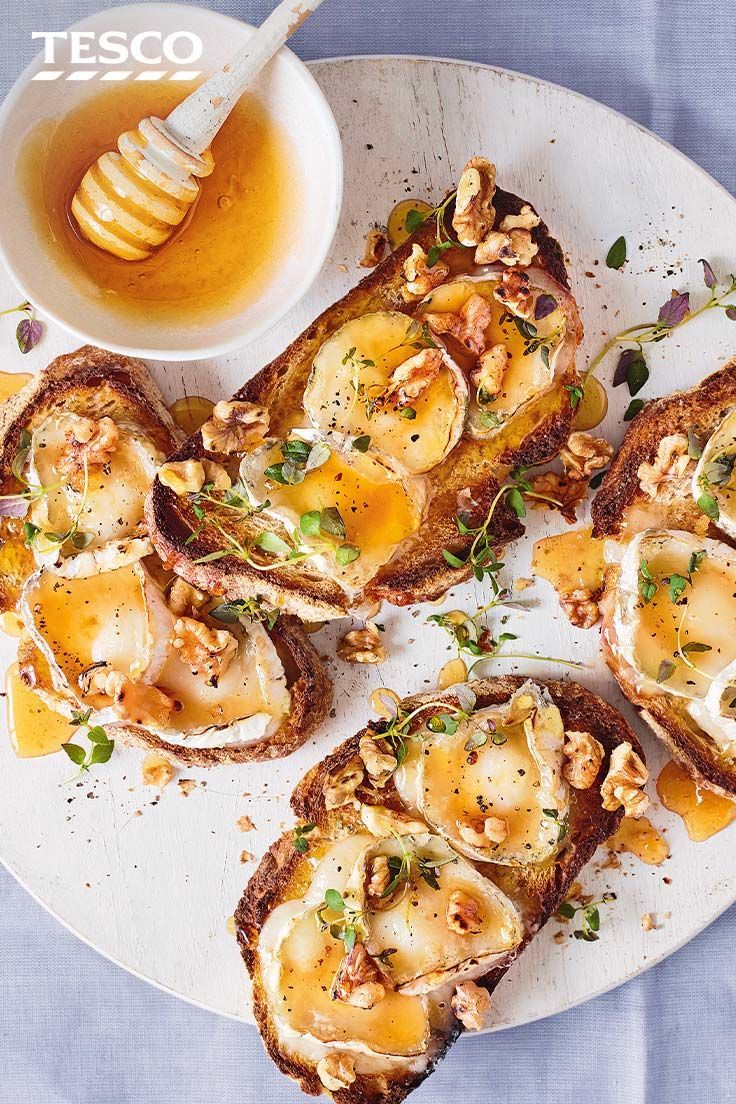 toasted bread topped with scallops and butter on a plate next to a bowl of honey