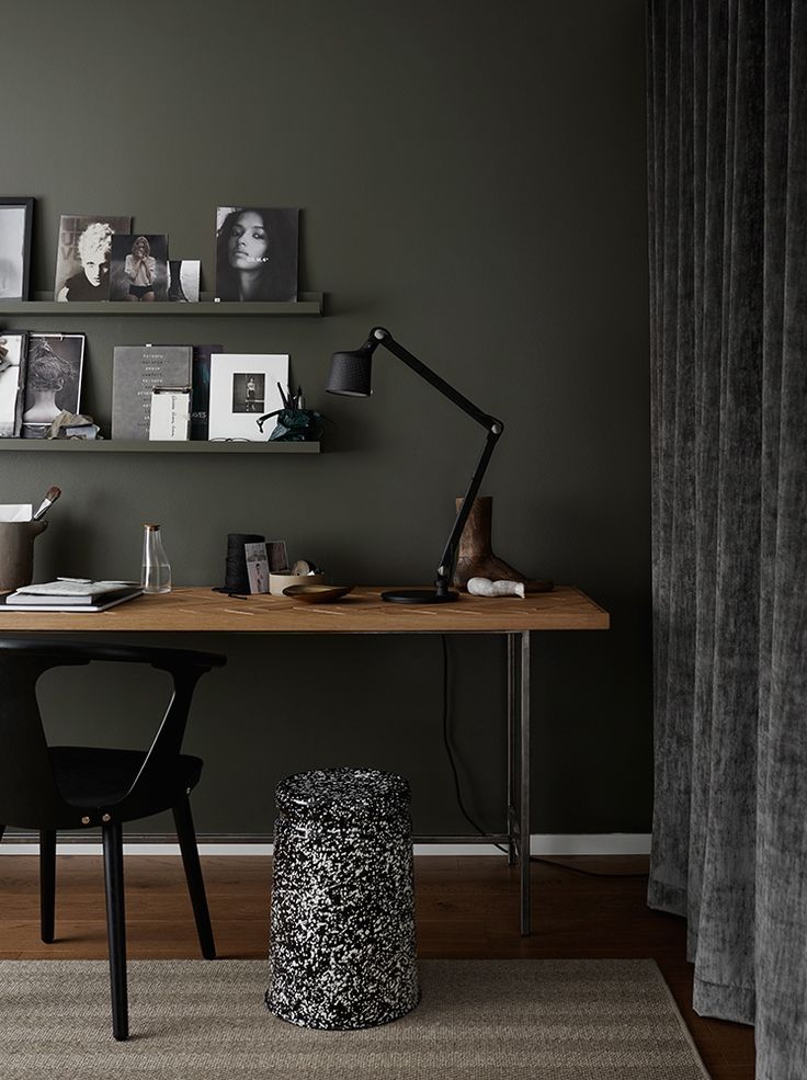 a desk with a lamp, bookshelf and pictures on the wall above it