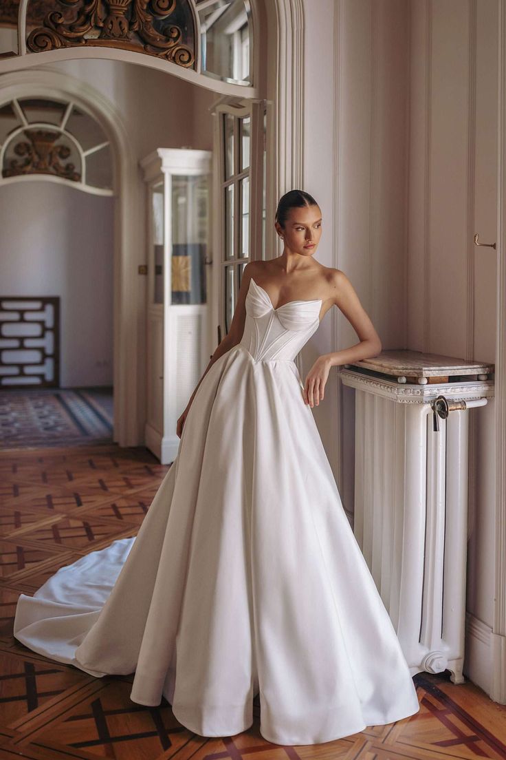 a woman in a white wedding dress posing for the camera