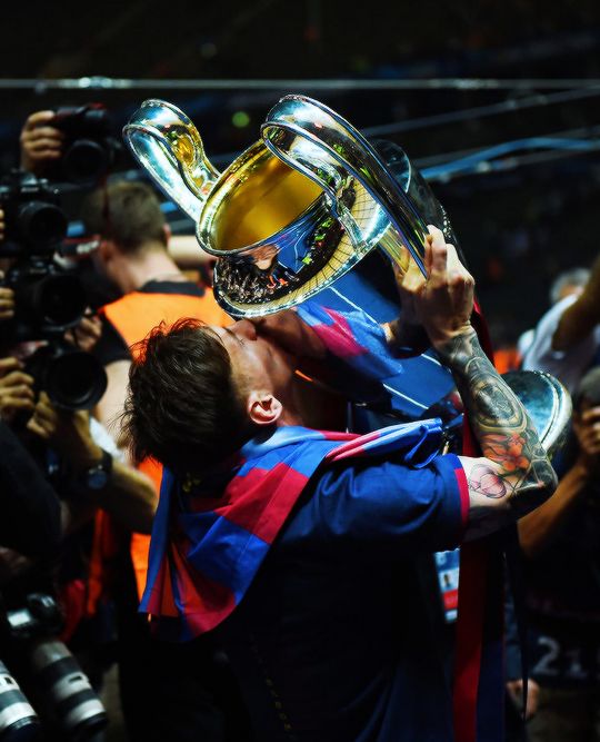 the soccer player is kissing the trophy in front of his team's fans and photographers