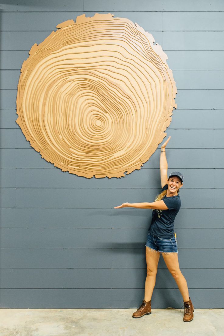 a woman is standing in front of a large wood piece that has been cut into the shape of a circle