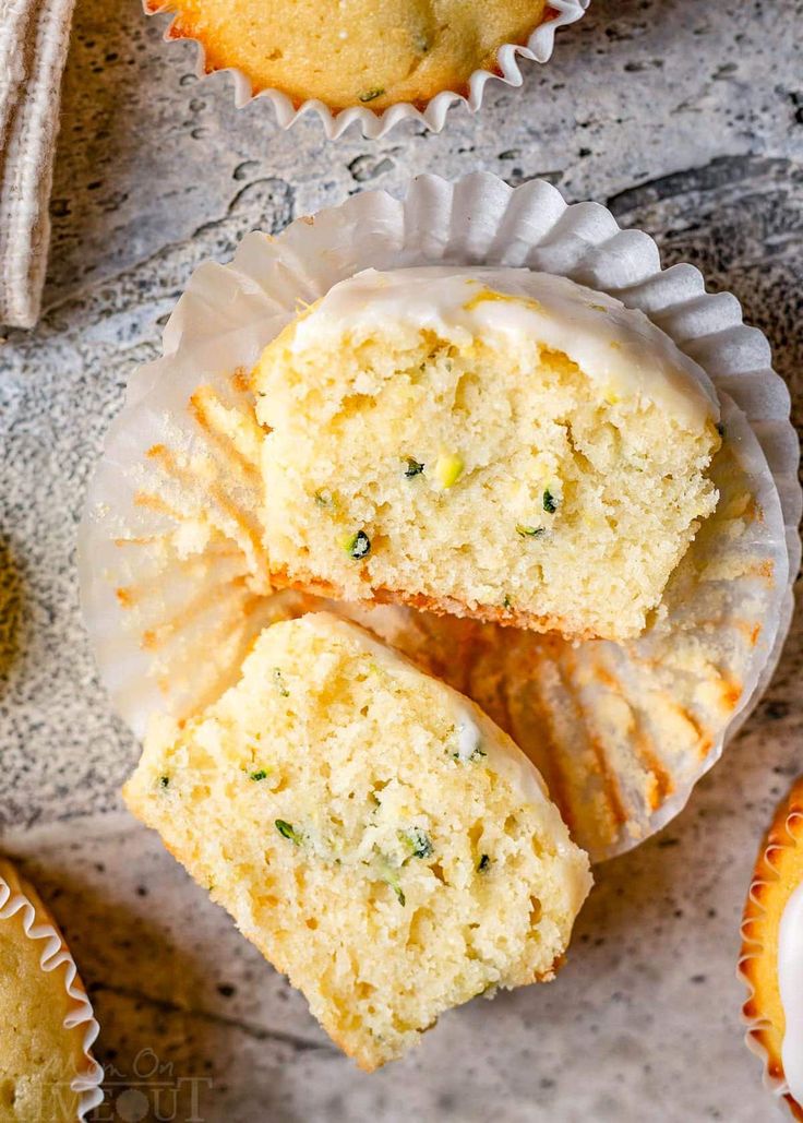 three muffins with white frosting and sprinkles sitting on top of each other