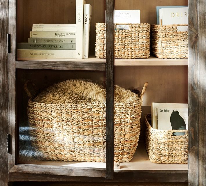 wicker baskets and books sit on shelves in a bookcase with wood trimmings