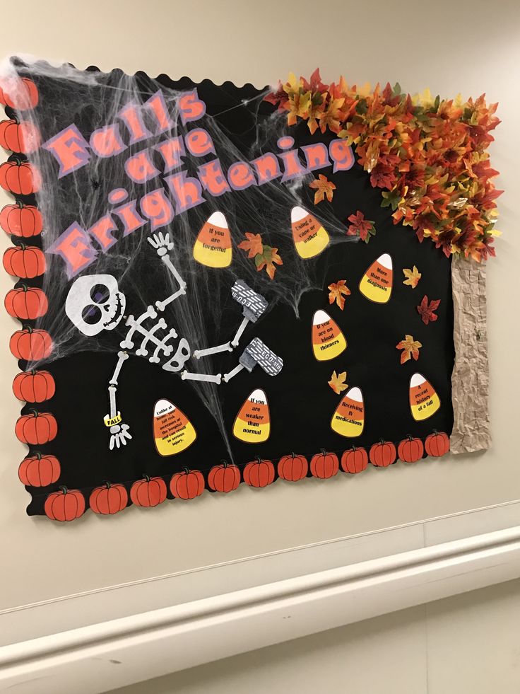 a bulletin board decorated with pumpkins, candy corn and a skeleton on it's side