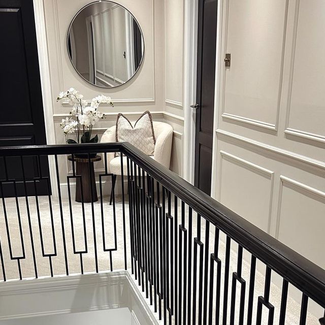 there is a mirror on the wall next to a stair case in this room with white walls and black railings