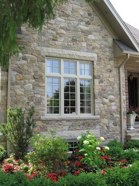 a stone house with lots of flowers in the front yard