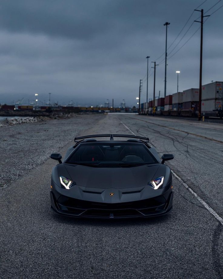 a black sports car is parked on the side of the road in front of an industrial area