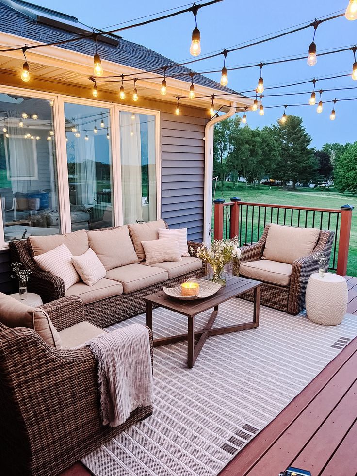 an outdoor patio with wicker furniture and string lights strung over the back porch area