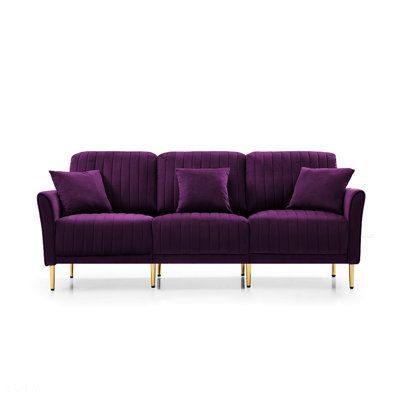 a purple couch with gold legs and pillows