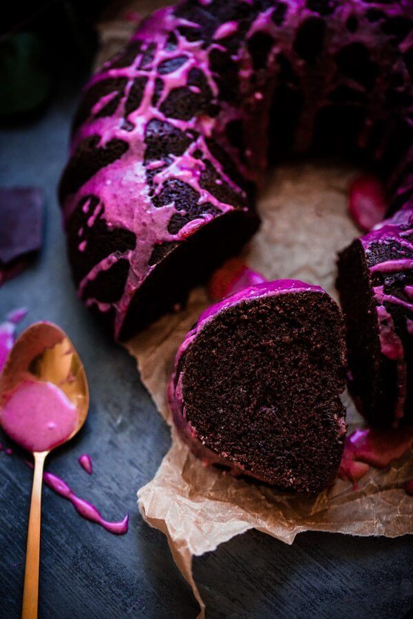 a chocolate bunt cake with purple icing on top and a spoon next to it