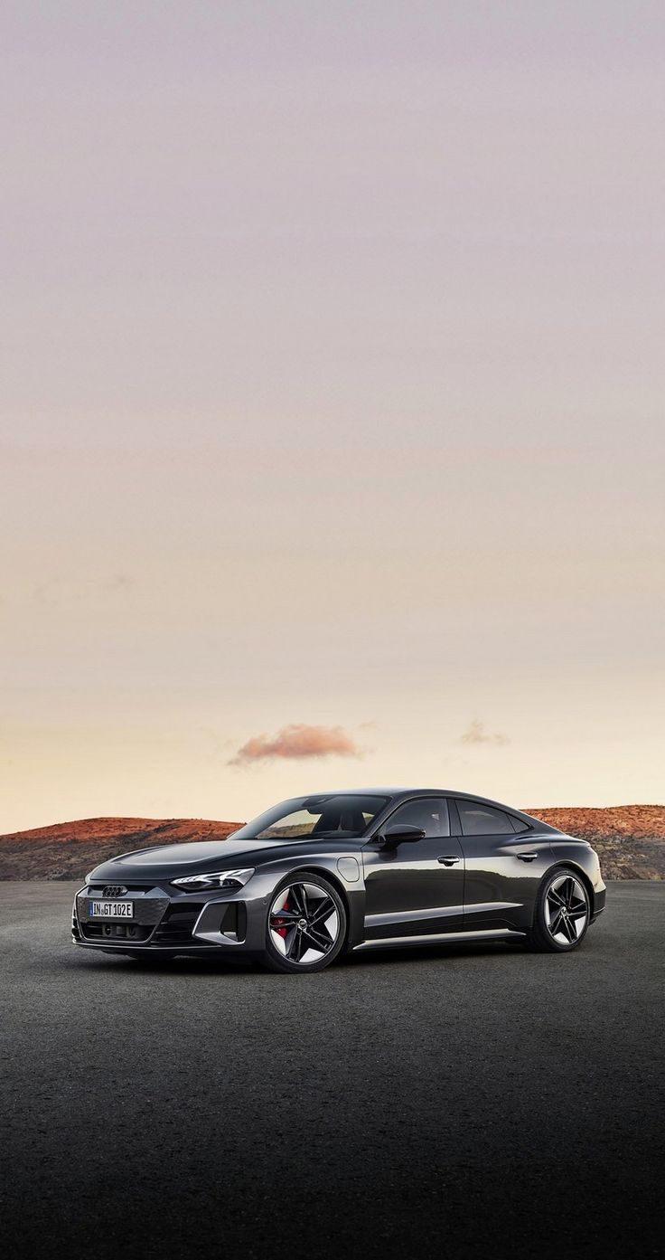 a black sports car parked on the side of a road in front of a mountain