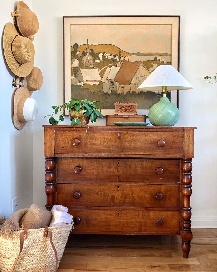 a wooden dresser sitting next to a wall with hats hanging on it's sides