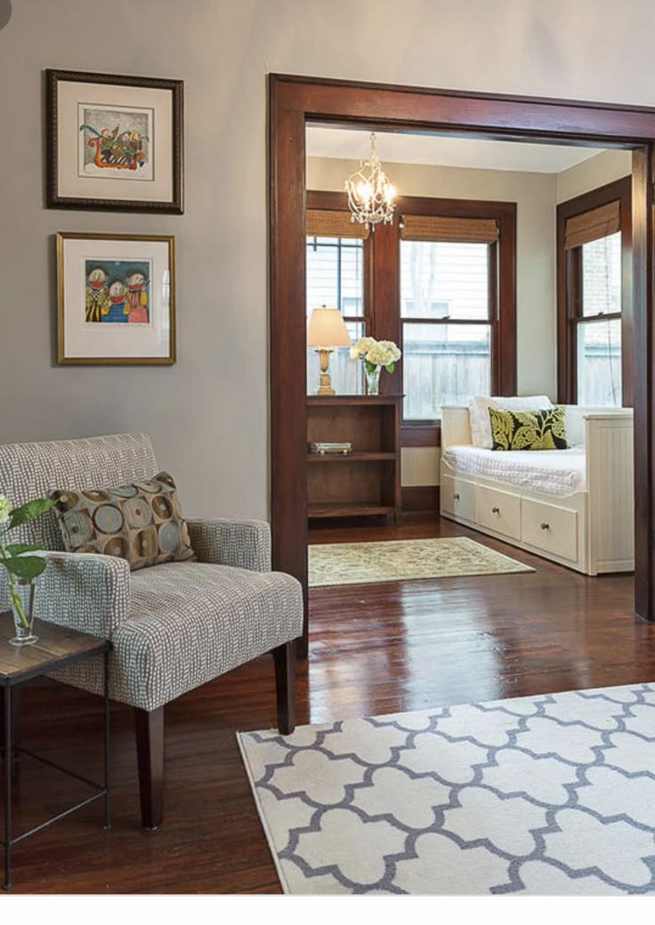 a living room filled with furniture and pictures hanging on the wall above a door that leads to a bedroom