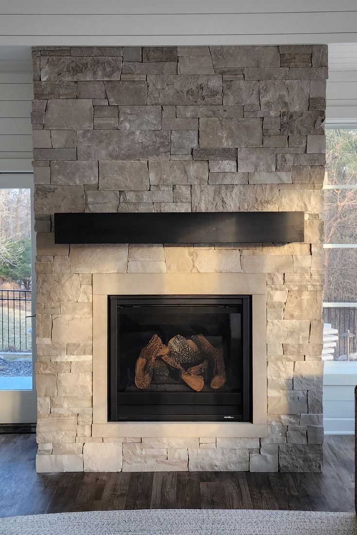 a stone fireplace in a living room with wood flooring