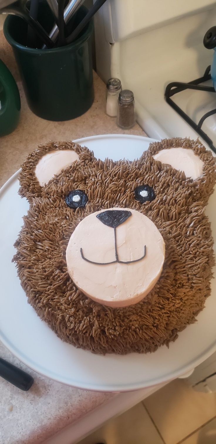 a cake shaped to look like a bear on a plate with utensils in the background