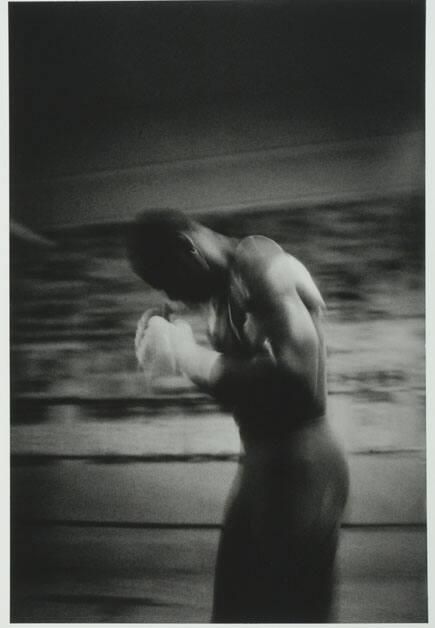 a black and white photo of a shirtless man in the middle of a boxing ring