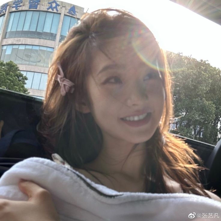 a woman sitting in the back seat of a car with a towel over her shoulder