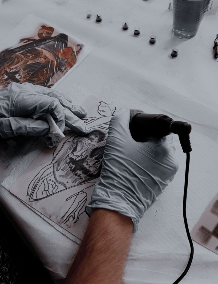 a man in gloves is drawing on a piece of paper with an electric heater