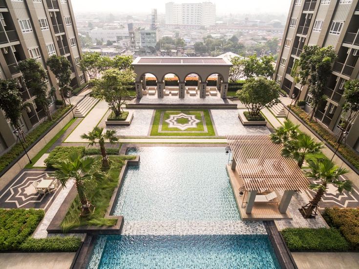 an aerial view of a swimming pool in a large building with many trees and lawns