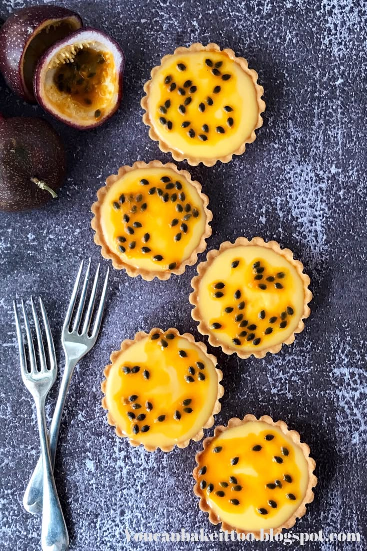 four small tarts with black seeds on them next to a fork and an avocado