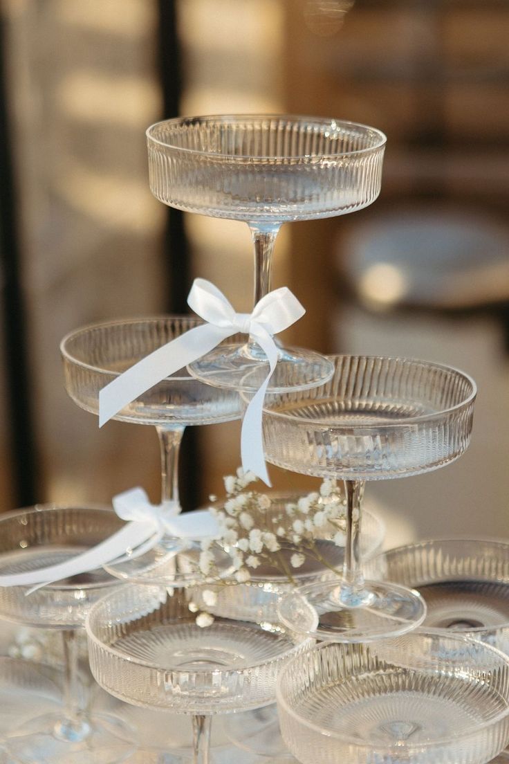 several wine glasses are stacked on top of each other with white ribbons and bowknots