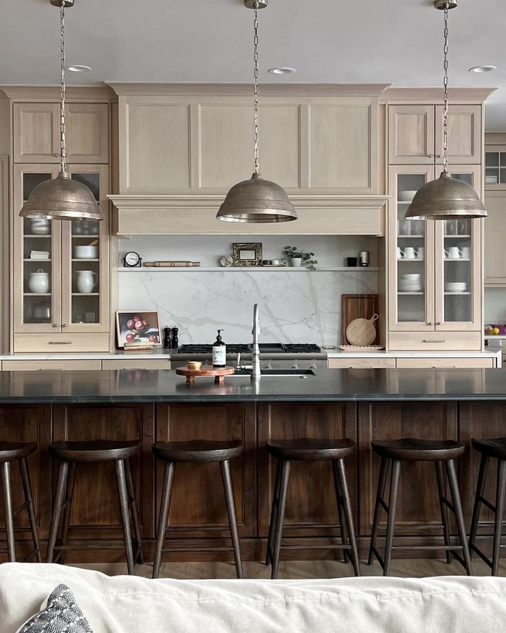 a kitchen with an island and bar stools next to it in front of the sink